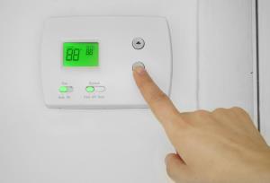 person adjusting the temperature on thermostat
